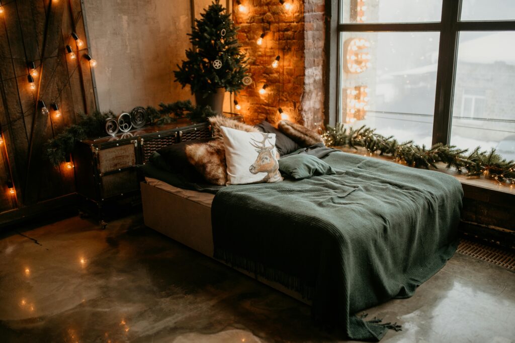 A warm and decorated bedroom featuring a Christmas tree and cozy bedding with soft lighting.