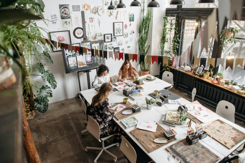 Women engaging in an artistic workshop, surrounded by art supplies and creative decor.