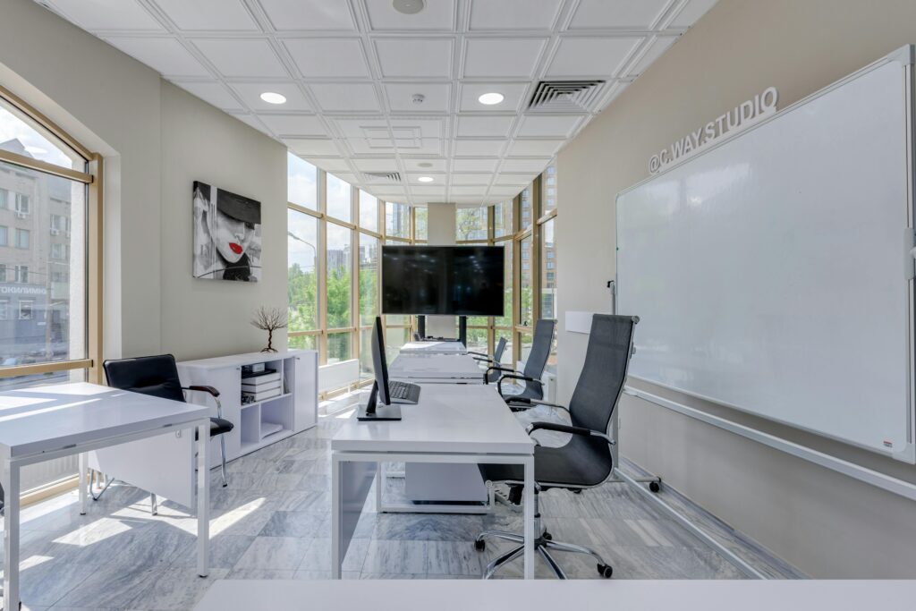 Spacious modern office interior featuring desks, office chairs, large windows, and a whiteboard.